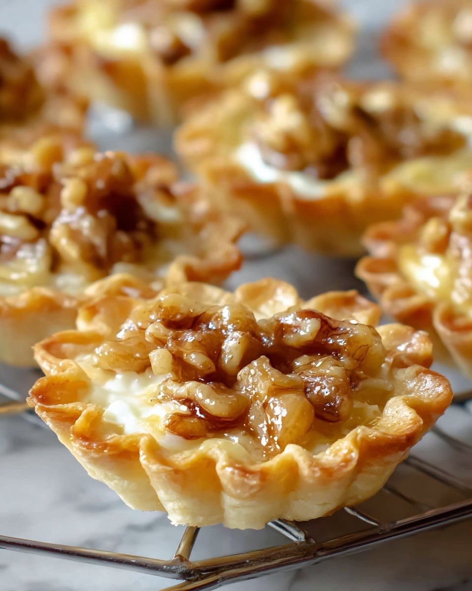 The image shows several small tarts placed closely together on a cooling rack over a white marbled surface. Each tart has a single thin layer of golden, flaky crust shaped with ruffled edges forming a cup. Inside, the filling is creamy and light yellow with a smooth texture, topped with chunks of glossy caramelized walnuts that add a rich brown and golden shine. The varied shades of brown from the nuts contrast with the shiny, smooth custard, creating an inviting, fresh-baked look. Photo taken with an iphone --ar 4:5 --v 7