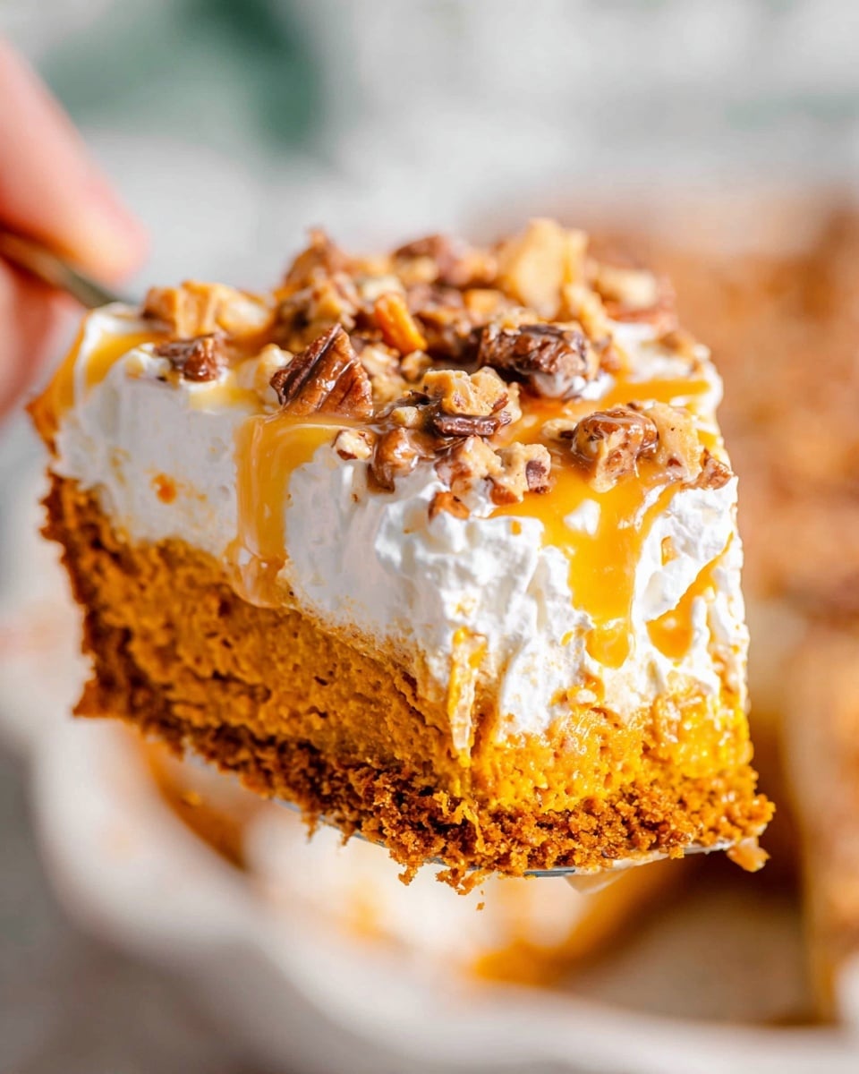 The image shows a close-up of a slice of pumpkin pie held by a woman's hand, focusing on its detailed layers. The bottom layer is a dense, moist orange pumpkin filling with a slightly crumbly texture. Above this is a thick layer of white, fluffy whipped topping that looks light and creamy. On top of the whipped layer is a drizzle of golden caramel sauce, adding a shiny, smooth contrast. Sprinkled over the caramel are small chunks of brown and tan nuts and toffee bits, providing a crunchy texture. The background has a white marbled texture, and the pie is placed in a white dish. photo taken with an iphone --ar 4:5 --v 7