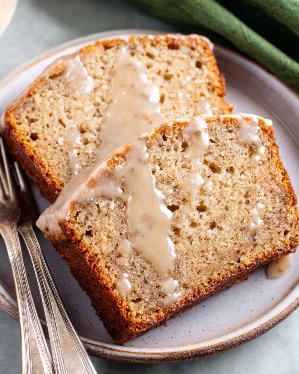 Two slices of moist banana bread with a light brown color and visible small air holes are placed on a white plate. The slices have a slightly darker golden brown crust around the edges and are drizzled with a thin layer of creamy white glaze that shines softly. The plate sits on a white marbled surface, and there are two vintage silver forks beside the slices. A green cloth is partially visible in the top right corner. photo taken with an iphone --ar 4:5 --v 7