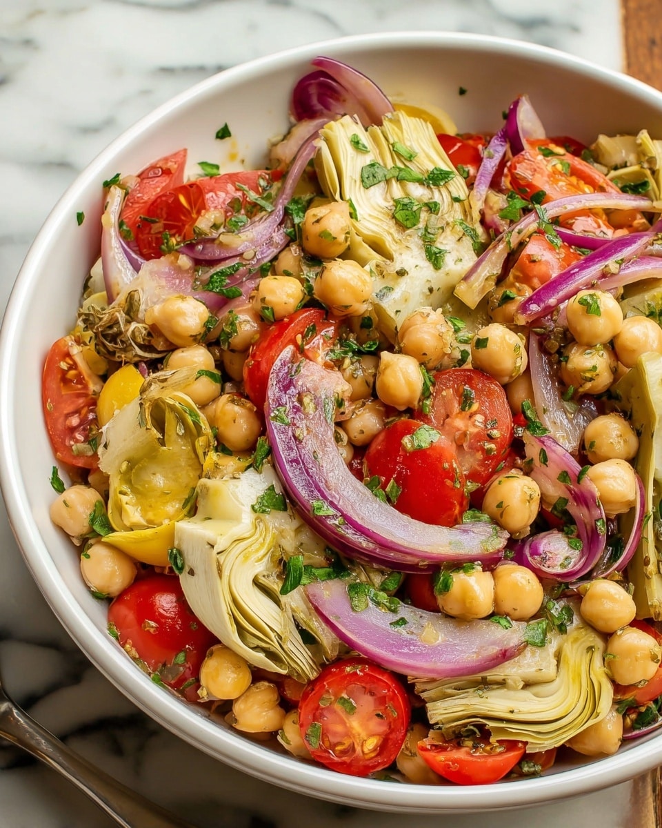 A close-up of a white bowl filled with a colorful veggie salad. The bottom layer contains chopped green herbs scattered around, topped with round yellow chickpeas and sliced pale yellow artichoke hearts arranged upright near the edge. Bright red cherry tomato halves and thin rings of purple-red onion are mixed throughout, adding contrast. Small green scallion pieces and a few capers are spread over the top, giving texture and color variety. The salad looks fresh and lightly dressed, set against a white marbled surface. photo taken with an iphone --ar 4:5 --v 7