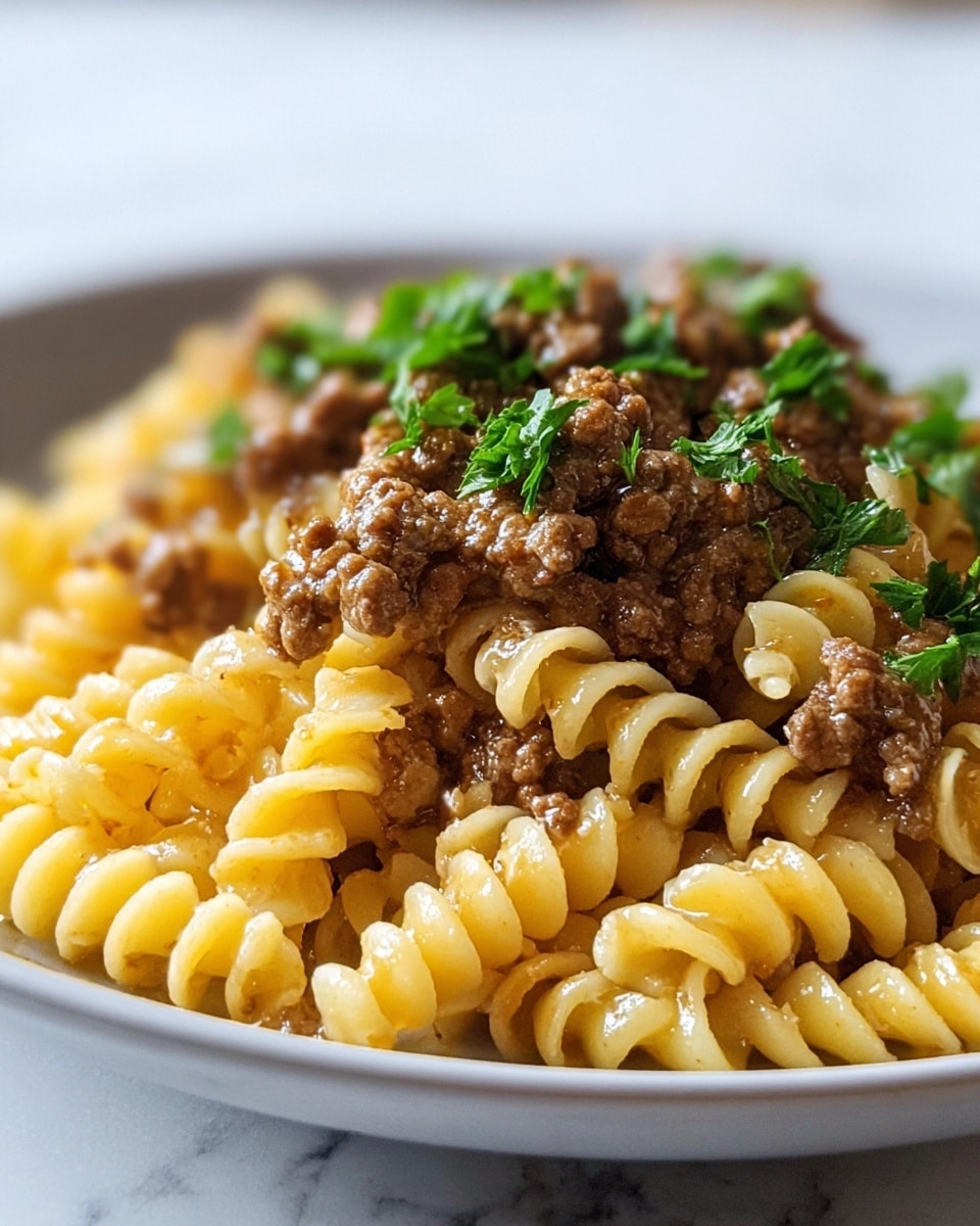 The image shows a close-up of a pasta dish served in a white plate on a white marbled surface. The dish has two main layers: at the bottom are yellow spiral pasta pieces with a slightly glossy texture, arranged to fill the plate. On top is a thick layer of brown minced meat sauce, rich and chunky, mixing into the pasta. Green parsley leaves are sprinkled over the meat sauce, adding a fresh touch of color. Photo taken with an iphone --ar 4:5 --v 7