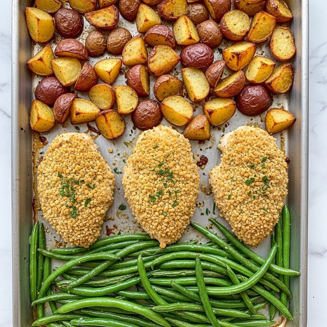 The image shows a golden baking tray filled with a meal made of three main parts. On the top section, there are plenty of small, cubed roasted potatoes with red skin, lightly browned and sprinkled with chopped green parsley. Below the potatoes in the center are three large pieces of breaded chicken breasts, crispy and golden brown, also topped with bits of chopped green parsley. The bottom section has bright green steamed or sautéed green beans, arranged neatly and glistening with a light coat of oil. The whole scene is set on a white marbled textured surface. Photo taken with an iphone --ar 4:5 --v 7
