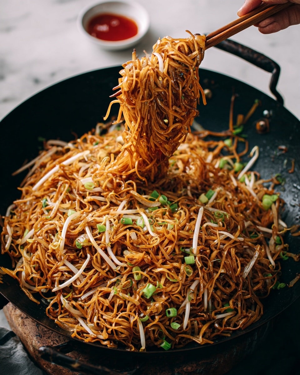 This image shows a large black wok filled with cooked thin noodles that are golden brown with slight glossiness. Mixed inside the noodles, there are pale white bean sprouts and light green sliced spring onions scattered on top and throughout, adding color contrast. A woman's hand is lifting a large clump of noodles with wooden chopsticks from the wok, showing the tangle of noodles stretching upwards. The background is a white marbled surface with some small bowls of sauce partially visible near the edges. The overall look is warm, textured, and full of detail. photo taken with an iphone --ar 4:5 --v 7